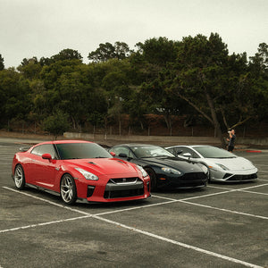 Red Nissan R35 GTR, Aston Martin Vantage, and Lamborghini Gallardo in a parking lot hanging out
